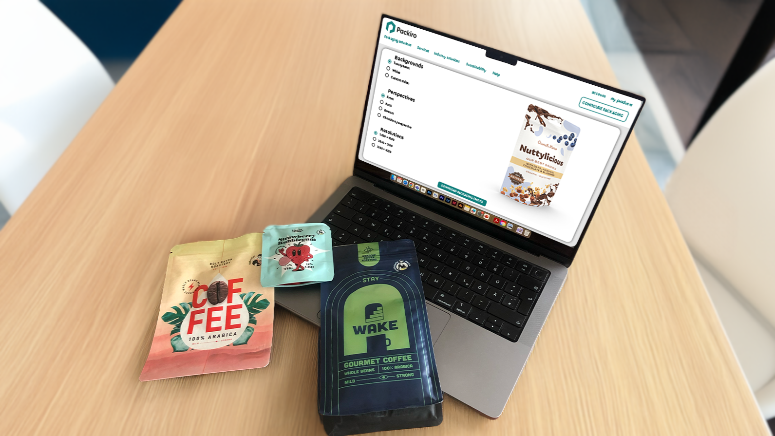 Laptop mit dem Packiro Designcheck auf einem Tisch mit bunten, flexiblen Verpackungen