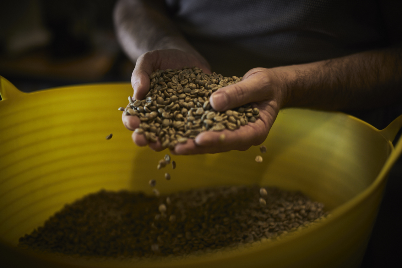 Handy gefüllt mit Kaffeebohnen über einer großen Schüssel