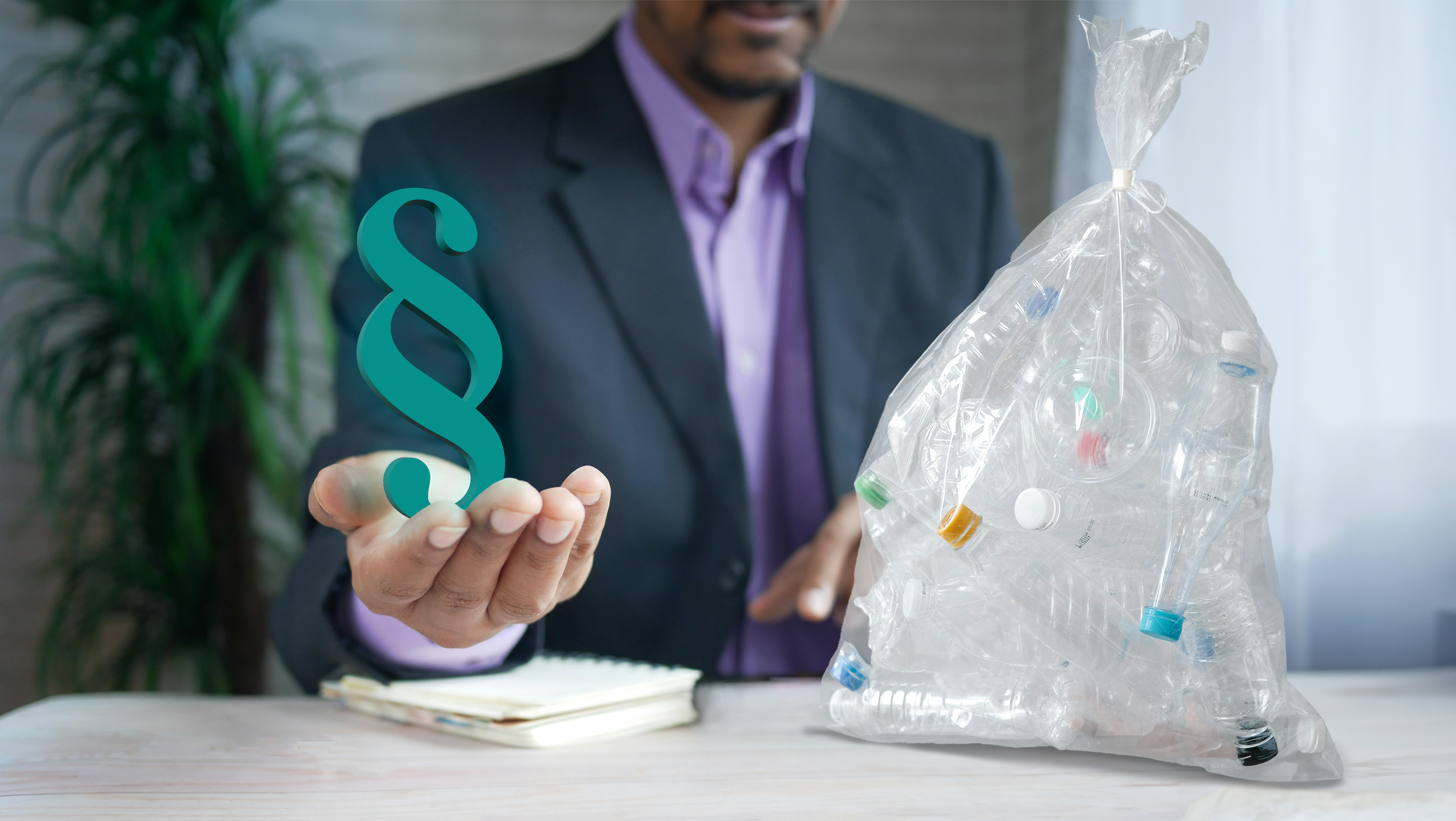 Mann im Anzug mit einem Paragraph-Symbol in der Hand und einem Plastikmüllbeutel vor sich