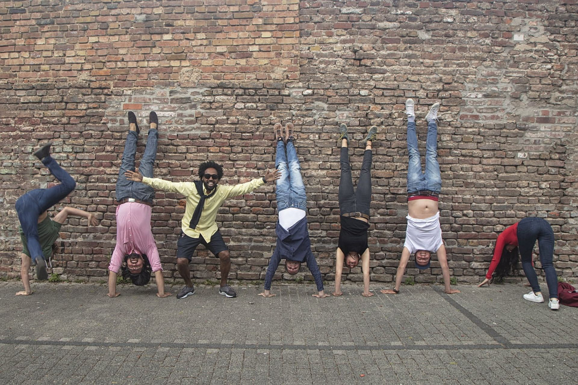 Teammitglieder von Plastic2Beans machen ein Handstand an einer Mauer