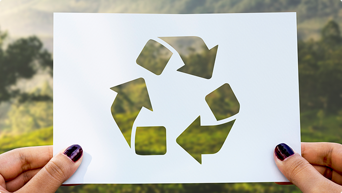 Hände die ein Blatt Papier mit dem Recyclingsymbol halten